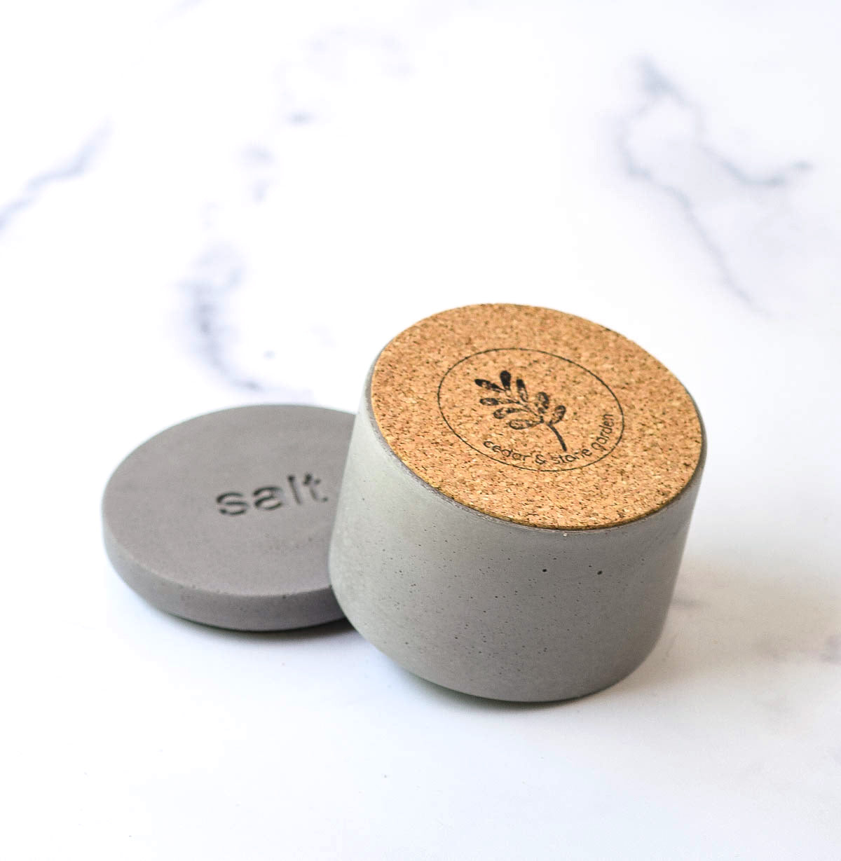 gray salt cellar with lid off turned over so protective cork bottom is visible.